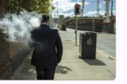 Man smoking while walking on a city sidewalk, legal etiquette in Japan
